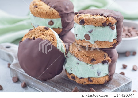 Chocolate covered ice cream sandwiches, mint chocolate chips ice cream , on wooden board, horizontal Chocolate covered ice cream sandwiches, mint chocolate chips ice cream , on wooden board, horizontal 114420344