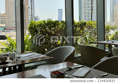 A neatly arranged restaurant table with dining ware and condiments, overlooking a city view 114420835