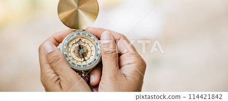 Surrounded by the beauty of nature a woman's hand grips a compass in a tranquil forest and lake setting. The image symbolizes guidance and the exciting spirit of exploration amidst the outdoors. Surrounded by the beauty of nature a woman's hand grips a compass in a tranquil forest and lake setting. The image symbolizes guidance and the exciting spirit of exploration amidst the outdoors. 114421842