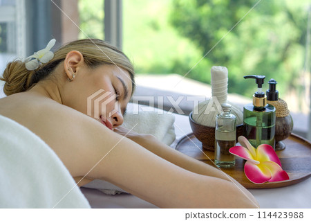 Holistic luxury wellness experience. A serene woman reclining leisurely within a soothing spa ambiance, surrounded by elements promoting tranquility. 114423988