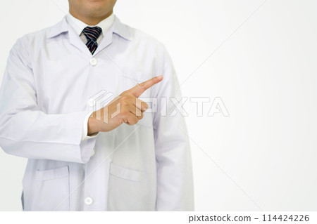 Healthcare professional in white lab coat stand in front of plain, white background, pointing to the right as if indicating a direction or highlighting a point of interest, explaining or presenting. 114424226