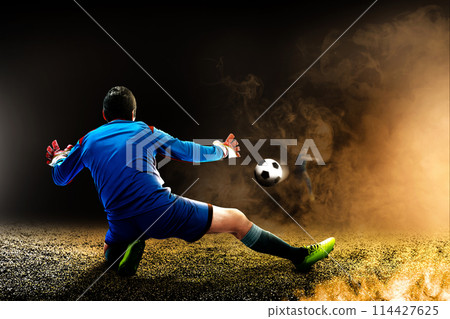 Portrait of a male goalkeeper trying to stop the ball on the pitch 114427625