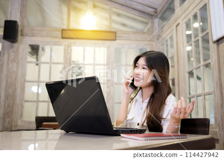 Portrait of businesswoman with laptop talking on the mobile phone to her business colleagues Portrait of businesswoman with laptop talking on the mobile phone to her business colleagues 114427942