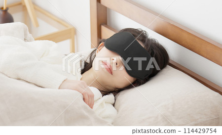 A woman sleeping with an eye mask in a bright room A woman sleeping with an eye mask in a bright room 114429754