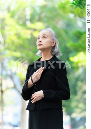 穿著喪服的老婦人抬頭看著新鮮的綠色植物 114430646