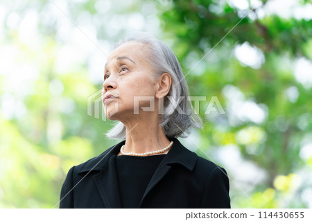 穿著喪服的老婦人抬頭看著新鮮的綠色植物 114430655