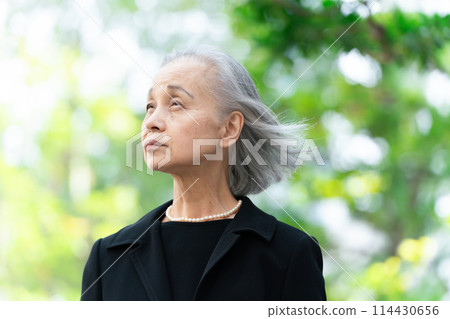 穿著喪服的老婦人抬頭看著新鮮的綠色植物 114430656