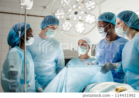 happy cheerful diverse doctors standing around the partient's bed happy cheerful diverse doctors standing around the partient's bed 114431992