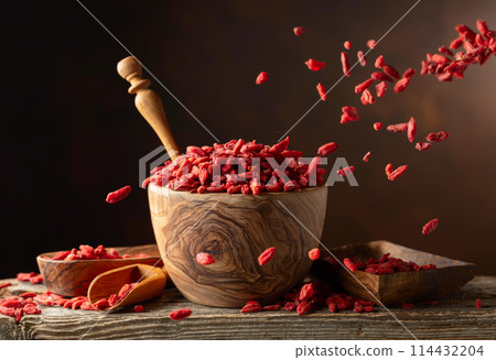 Dried goji berries in wooden bowl on a brown background. Dried goji berries in wooden bowl on a brown background. 114432204