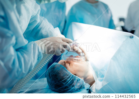 doctor in gloves holding the oxygen mask firmly against patient's face. doctor in gloves holding the oxygen mask firmly against patient's face. 114432565