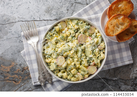 Delicious summer salad with boiled eggs, radishes, green onions and cucumber served with toasted bread close-up in a bowl. Horizontal top view 114433034