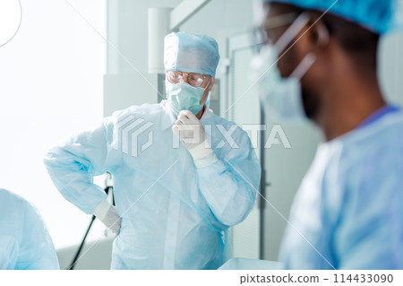 tired physician with close eyes touching surgical mask 114433090