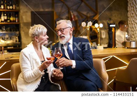 I like you. Sweet cheerful senior couple having date in restaurant while smiling and clink glasses 114433151