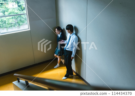 High school students talking on the landing of the stairs High school students talking on the landing of the stairs 114434370