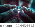 Craftsman holding a brilliantly lit diamond ring, demonstrating the final product of skilled jewelry work 114434418