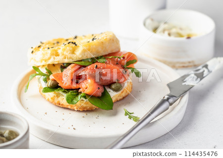 Homemade bagel sandwich with smoked salmon, cream cheese, capers and spinach for healthy breakfast on white kitchen background for breakfast 114435476