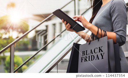 Woman Using Tablet and Holding Black Friday Shopping Bags - Generative Ai 114437354