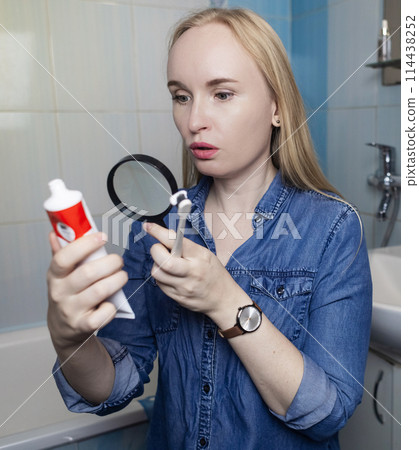 Toothpaste ingredients. Girl checks composition of toothpaste and is surprised by dangerous composition of product. Emulsifiers, preservatives, dyes, PEG, SLS, parabens, diethanolamine Toothpaste ingredients. Girl checks composition of toothpaste and is surprised by dangerous composition of product. Emulsifiers, preservatives, dyes, PEG, SLS, parabens, diethanolamine 114438252