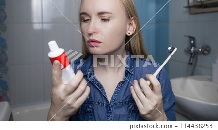 Toothpaste ingredients. Girl checks composition of toothpaste and is surprised by dangerous composition of product. Emulsifiers, preservatives, dyes, PEG, SLS, parabens, diethanolamine 114438253