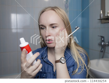 Toothpaste ingredients. Girl checks composition of toothpaste and is surprised by dangerous composition of product. Emulsifiers, preservatives, dyes, PEG, SLS, parabens, diethanolamine 114438254