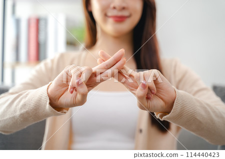 A young deaf woman is sitting on a couch and making a sign Language to communicate. 114440423