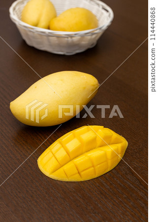 Mango. Close up of fresh ripe mango fruit with leaves over dark wooden table background with green leaves Mango. Close up of fresh ripe mango fruit with leaves over dark wooden table background with green leaves 114440868