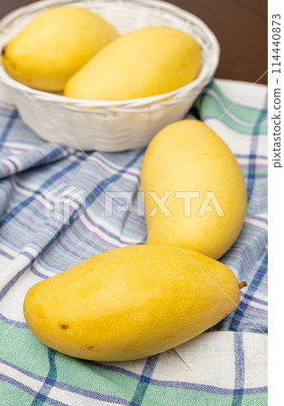 Ripe mango fruits in basket with leaves on wooden table at garden. 114440873