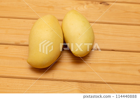Stack of ripe mangoes fruit on wooden table with green nature at farm 114440888