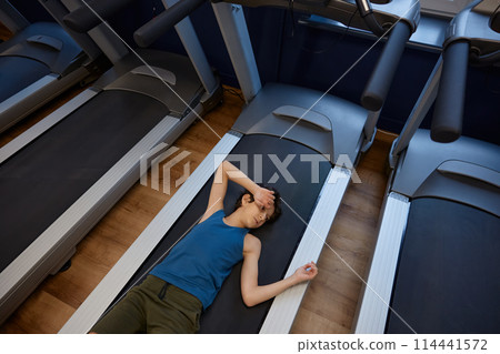 Exhausted boy lying on treadmill feeling need of recharge and recovery 114441572