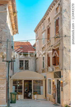 Rovinj, Croatia. Picturesque Mediterranean street with outdoor cafes people walking summer sun. 114443370