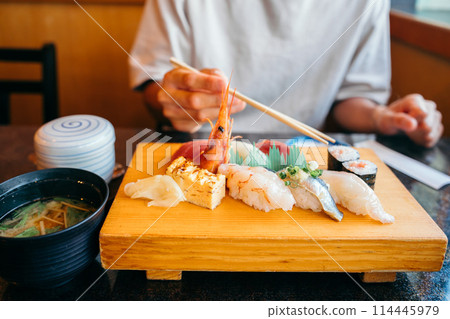 Hands of a man eating sushi Hands of a man eating sushi 114445979