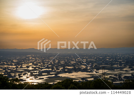 A beautiful sunset view of the sun reflecting off a flooded rice field | Taken from Sankyomura Observation Plaza | Tonami City, Toyama Prefecture 114449028