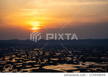 A beautiful sunset view of the sun reflecting off a flooded rice field | Taken from Sankyomura Observation Plaza | Tonami City, Toyama Prefecture 114449044