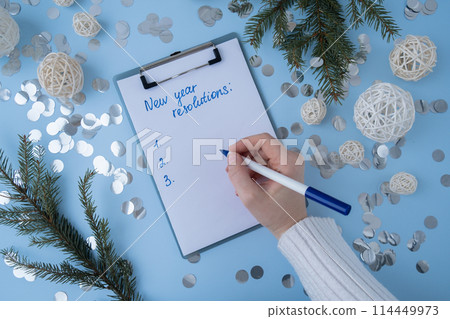 Female hands writing handwritten new year resolutions aims goals on paper notepad. Preparation for New Year. Planning and setting goals for personal development Female hands writing handwritten new year resolutions aims goals on paper notepad. Preparation for New Year. Planning and setting goals for personal development 114449973