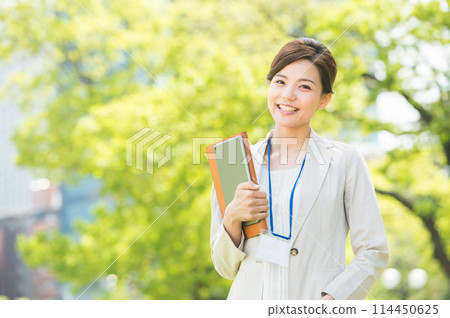 A woman in a suit smiling among the fresh greenery A woman in a suit smiling among the fresh greenery 114450625