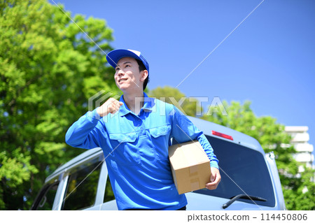 A male delivery driver carrying luggage outdoors A male delivery driver carrying luggage outdoors 114450806