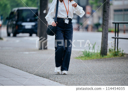 一位年輕女子邊走邊擔心時間 一位年輕女子邊走邊擔心時間 114454035