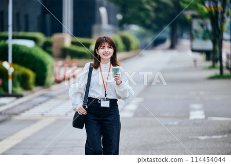 拿著咖啡杯走路的年輕女子 114454044