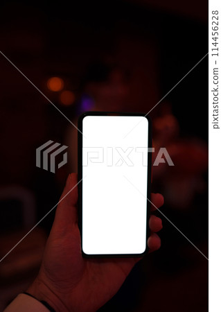Person holding a portable communications device with a white display screen Person holding a portable communications device with a white display screen 114456228