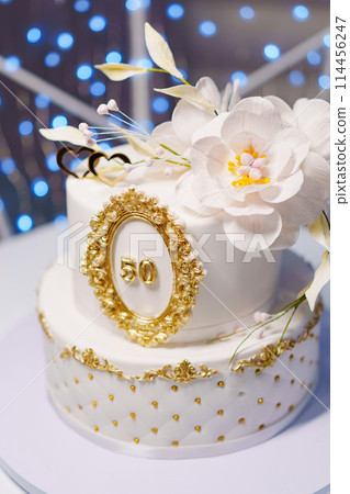 Beautiful white two-tiered cake decorated with flowers. 50th Anniversary Cake. 114456247