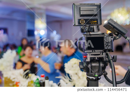 A professional camera on the blurred background of a banquet hall. A professional camera on the blurred background of a banquet hall. 114456471