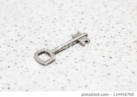 Close up of a nickel key on a white surface, a shiny metal accessory Close up of a nickel key on a white surface, a shiny metal accessory 114456700