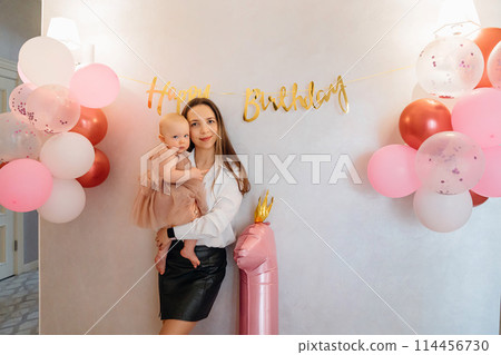 Cute baby daughter in an elegant dress with her mother. home party Cute baby daughter in an elegant dress with her mother. home party 114456730