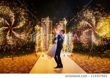 The bride and groom on the wedding ceremony venue with fireworks at night . The bride and groom on the wedding ceremony venue with fireworks at night . 114457081