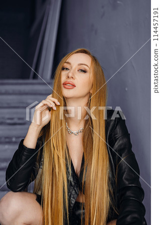 Beautiful young red-haired long-haired woman in black leather shirt 114457191