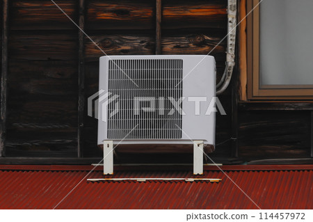 Old air conditioner outdoor unit attached to the roof 114457972