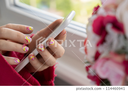 Woman manicured hands holding mobile phone, stylish summer colorful nails. Closeup of manicured nails of female hand. Summer style of nail design concept. Beauty Woman manicured hands holding mobile phone, stylish summer colorful nails. Closeup of manicured nails of female hand. Summer style of nail design concept. Beauty 114460941