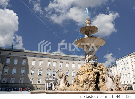 Salzburg, Austria, August 15, 2022. In the center of the Residenzplatz square the beautiful fountain with statues of prancing horses. People walk. 114461132