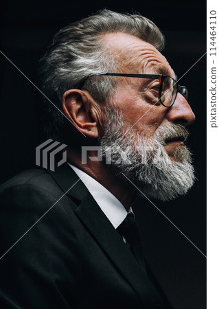 Head portrait of senior businessman posing in profile isolated over black wall 114464110