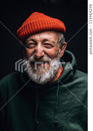 Happy 70-year-old optimist man with smiling wrinkled face, isolated on dark 114464299